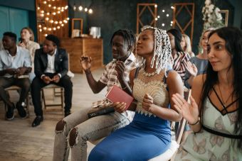 A diverse group of adults engaged in joyful prayer and worship indoors, expressing unity and faith.