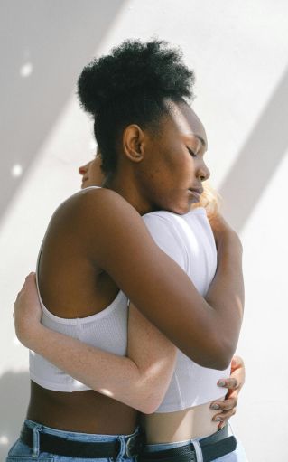 A loving embrace between an interracial couple in a bright, sunlit indoor setting, expressing warmth and affection.