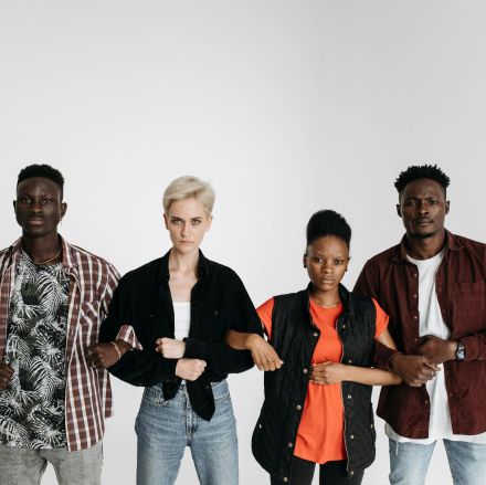 Five diverse adults standing together, linking arms, symbolizing unity and solidarity on a white background.