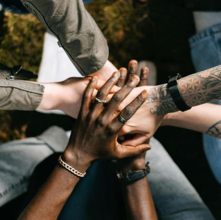 A group of diverse individuals placing their hands together in unity, symbolizing teamwork and collaboration.