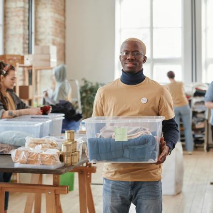 A group of diverse volunteers sorting and organizing clothes at an indoor donation center.